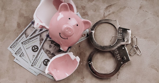 Broken piggy bank, handcuffs, and cash.