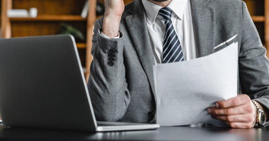 Male professional holding and studying documents.