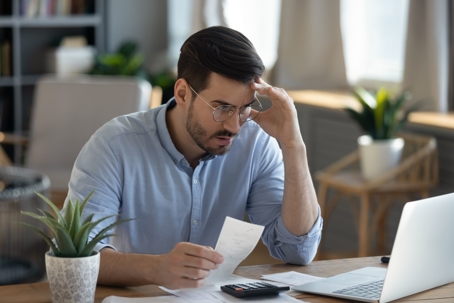 Man looking at laptop with hand on forehead